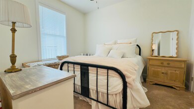 Bedroom featuring light colored carpet and multiple windows