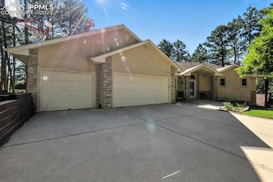 View of front of home with stone siding, stucco siding, driveway, and a garage