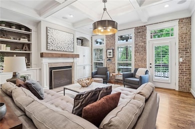 Living area featuring brick wall, coffered ceiling, a high end fireplace, light wood-style floors, and beamed ceiling