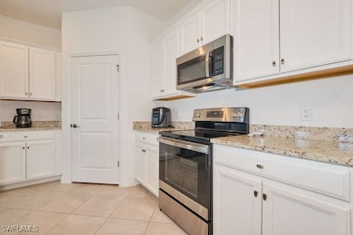 Kitchen with white cabinetry, light tile patterned
