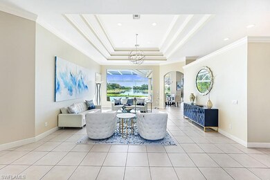 Living room featuring a notable chandelier, a raised ceiling, light tile patterned flooring, and crown molding