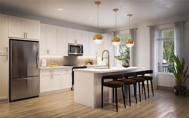 Kitchen featuring appliances with stainless steel finishes, tasteful backsplash, white cabinetry, a kitchen bar, and light wood-style flooring