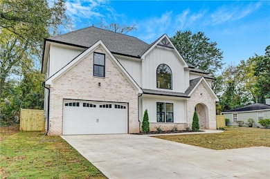 Modern farmhouse style home with board and batten siding, driveway, roof with shingles, a garage, and brick siding