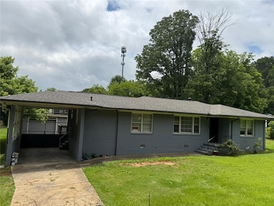Ranch-style home with concrete driveway, a carport, a front lawn, and crawl space