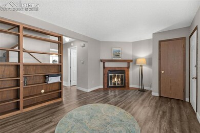 Living room featuring wood finished floors, a textured ceiling, baseboards, and a fireplace with flush hearth