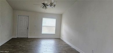 Spare room with dark wood-style floors, baseboards
