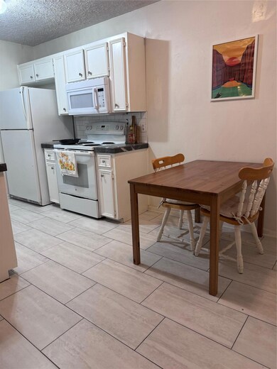Kitchen with white cabinets, dark countertops, ra