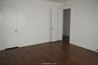 Spare room featuring wood finished floors, baseboa