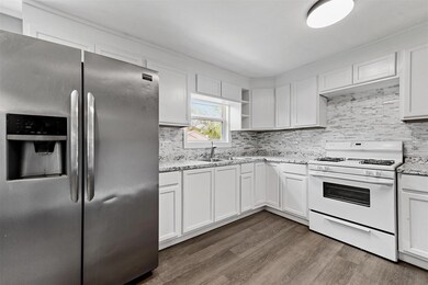 Kitchen featuring gas range gas stove, stainless steel refrigerator with ice dispenser, dark hardwood / wood-style flooring, sink, and tasteful backsplash
