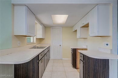 Kitchen with a sink, white cabinetry, light tile p