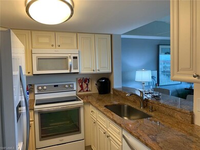 Kitchen featuring white appliances, dark stone countertops, and white cabinets
