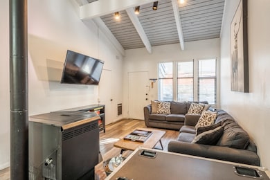 Living area with light wood-style flooring, a wooden ceiling with exposed beams, high vaulted ceiling, and heating unit