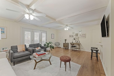 Living room featuring wood finished floors, beam ceiling, ceiling fan, coffered ceiling, and wooden walls