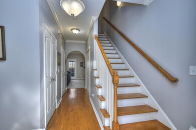 Staircase with arched walkways, baseboards, wood finished floors, and crown molding