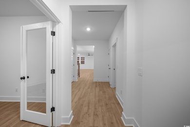 Hallway featuring light wood-style flooring, baseb