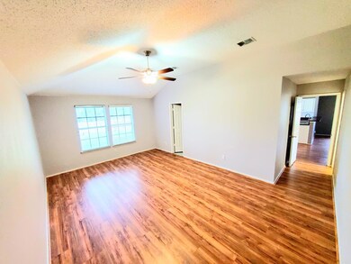 Spare room with a textured ceiling, lofted ceiling, ceiling fan, and hardwood / wood-style flooring