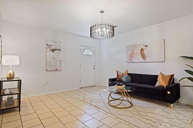 Living area with a chandelier, light tile patterned flooring, and baseboards