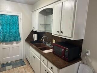 Kitchen featuring dark countertops, white cabinetr