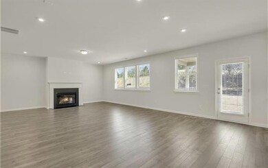 Unfurnished living room with wood finished floors, a fireplace with flush hearth, baseboards, and recessed lighting