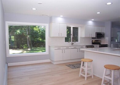 Kitchen with stainless steel appliances, light countertops, backsplash, a kitchen bar, and recessed lighting