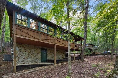 Back of property with stone siding, a wooden deck, and central air condition unit