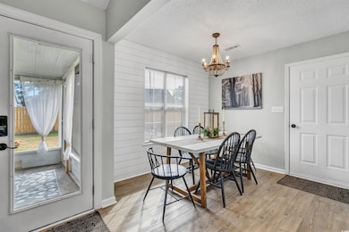 Dining area featuring a textured ceiling, light wood-style floors, a chandelier, and wooden walls