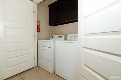 Laundry room featuring cabinet space, light tile patterned floors, and washer and clothes dryer