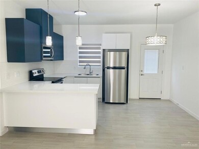 Kitchen with stainless steel appliances, light wood-style floors, light countertops, and pendant lighting