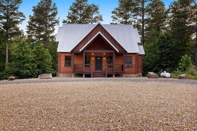 Log-style house featuring covered porch, a metal roof, and log veneer siding