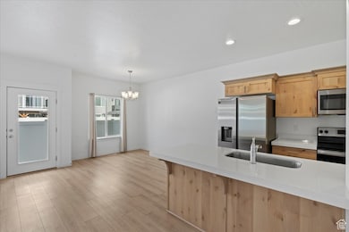 Kitchen featuring appliances with stainless steel finishes, light brown cabinets, hanging light fixtures, light wood-style flooring, and recessed lighting