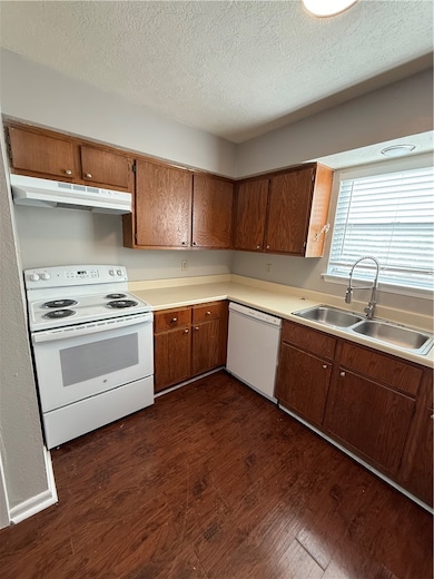 Kitchen featuring range, a textured ceiling, dark wood-type flooring, white dishwasher, and light countertops