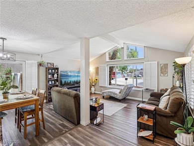 Living area with wood finished floors, a textured ceiling, and a chandelier
