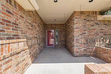 Property entrance featuring brick siding and a patio