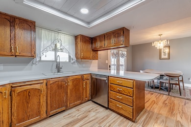 Kitchen featuring a peninsula, brown cabinetry, light countertops, light wood finished floors, and recessed lighting