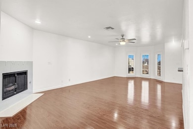 Unfurnished living room with light wood finished floors, a fireplace, and a ceiling fan