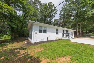 View of front of house with brick siding, crawl space, and view of wooded area