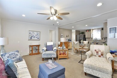 Carpeted living room with sink and ceiling fan