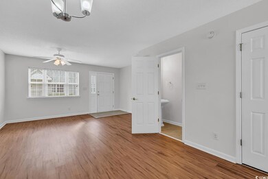 Interior space with light wood-style flooring, a textured ceiling, ceiling fan with notable chandelier, and baseboards