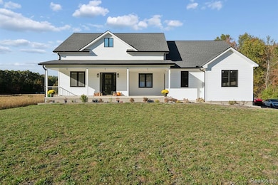 View of front of home with covered porch, a front yard, and roof with shingles