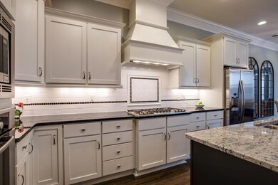 Gourmet Kitchen w/ Painted White Cabinets, gleaming granite, hardwood floors (which are throughout home), Bosch Stainless Steel Appliances including 5 Burner Gas Cooktop. Crisp white subway tile backsplash, island seating. Open to Family & Dining!