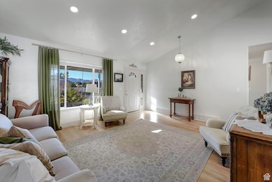 Living room with vaulted ceiling, light wood finished floors, and recessed lighting
