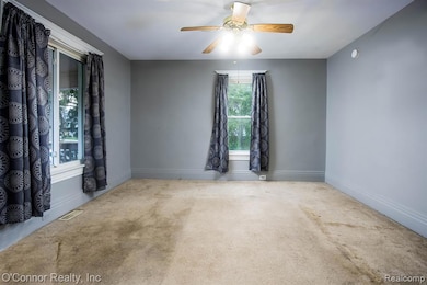 Carpeted empty room featuring ceiling fan and baseboards