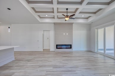 Unfurnished living room featuring a ceiling fan, light wood-type flooring, a fireplace, coffered ceiling, and beamed ceiling