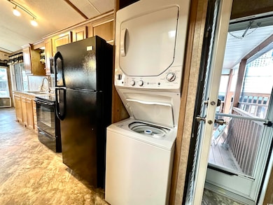 Laundry area with estacked washer and dryer and light stone finish flooring