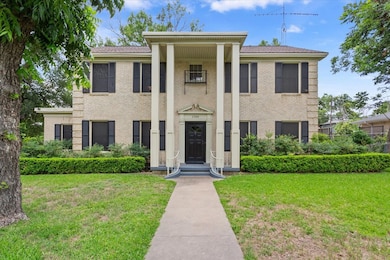 Greek revival inspired property featuring a front yard and brick siding
