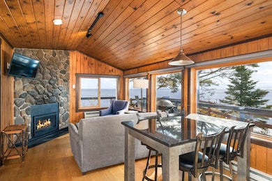 Dining area featuring hardwood / wood-style flooring, a fireplace, lofted ceiling, wood walls, and a water view