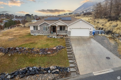 Single story home featuring an attached garage, concrete driveway, a lawn, roof mounted solar panels, and stucco siding