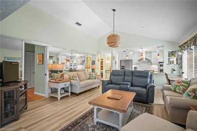 Living room with light wood-style floors, visible vents, and high vaulted ceiling