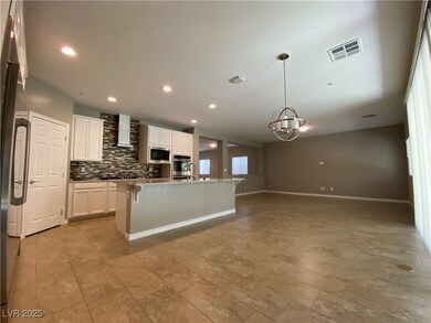 Kitchen with backsplash, a kitchen breakfast bar, white cabinetry, a kitchen island with sink, and wall chimney range hood