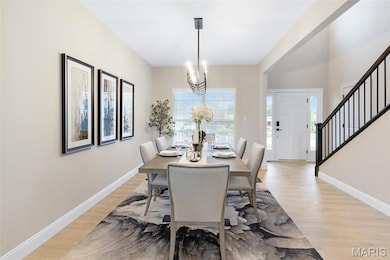 Dining area featuring stairs, light wood finished floors, and a chandelier